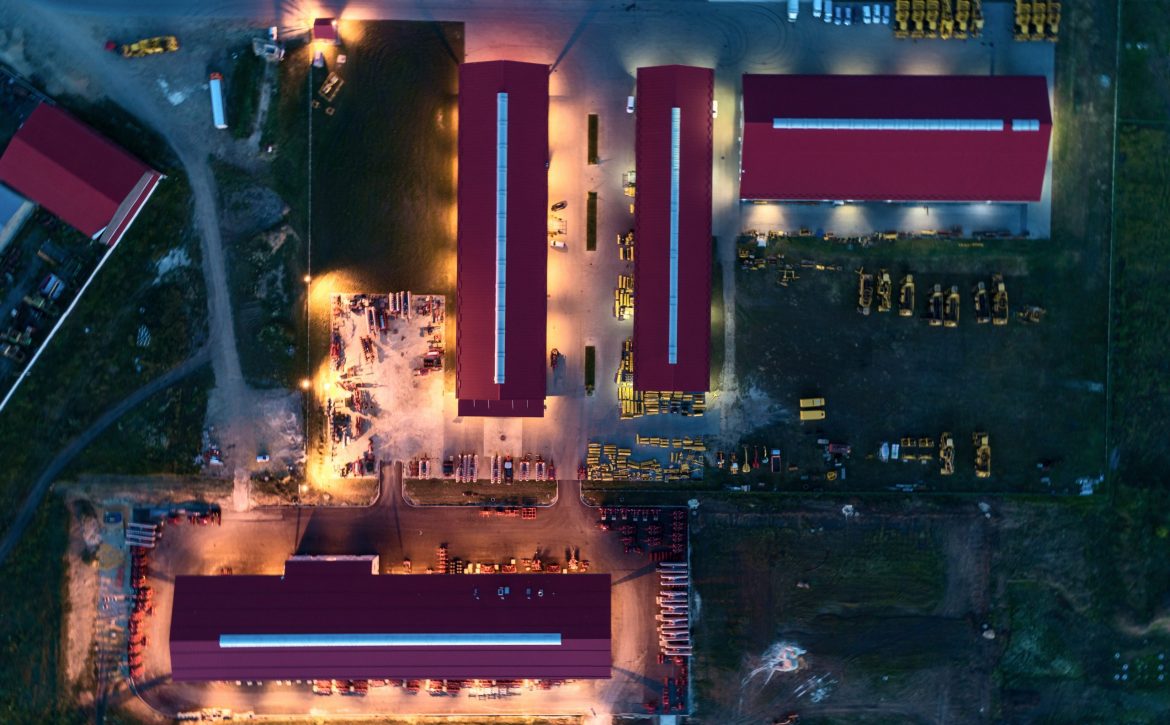 The territory of an industrial plant. Large hangars with a red roof. Aerial view, night shooting
